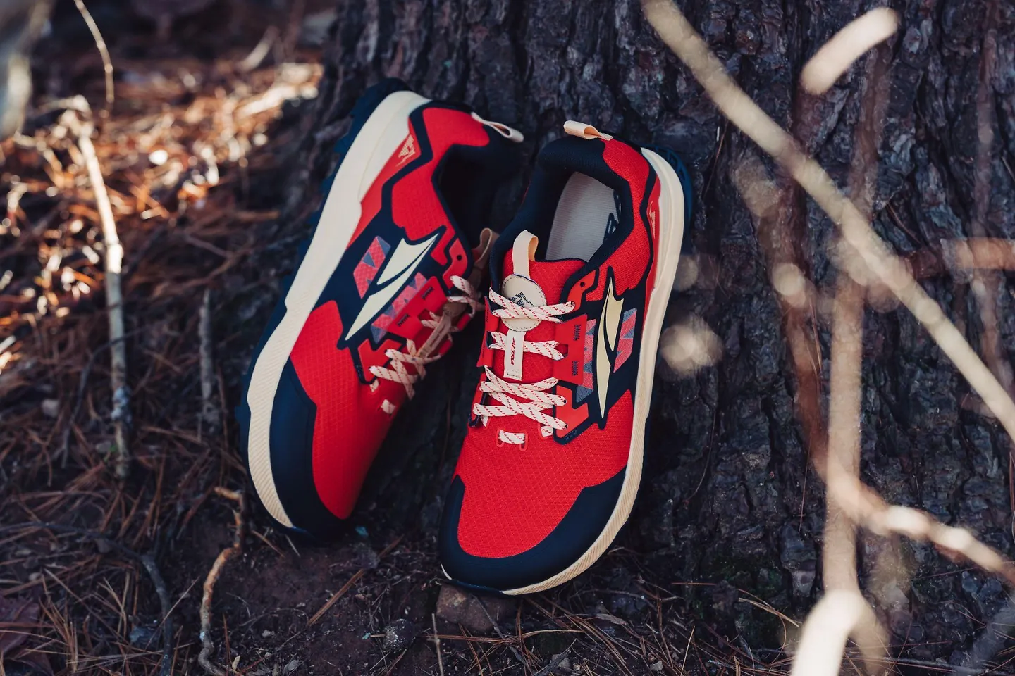 A pair of the Altra Lone Peak 7 men's shoe stands against a tree.