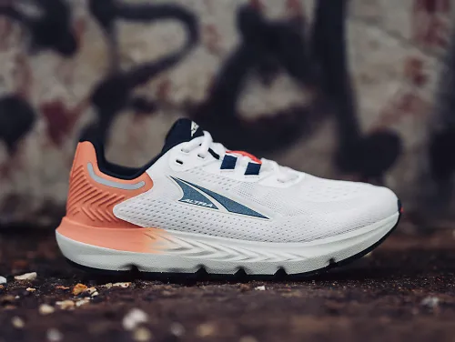 The Altra Provision 7 in a white and pink colorway sits atop a brick patio.