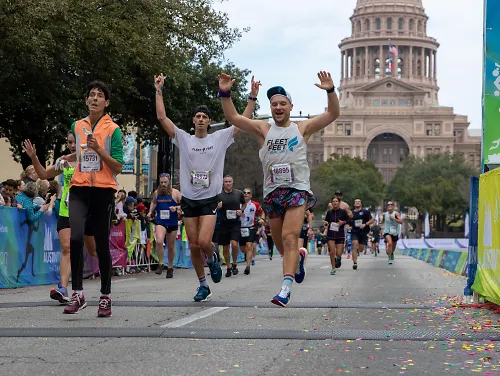 Runners celebrate while crossing the finish line of the 2022 Austin Marathon. 
