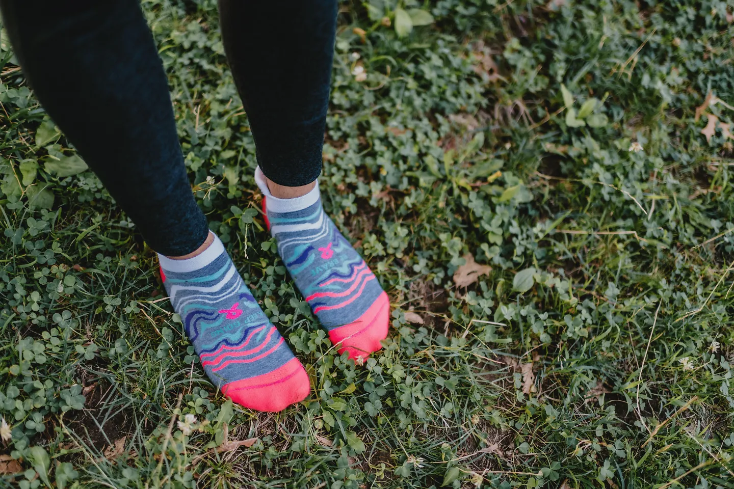 A woman stands in the grass in her Balega running socks. 