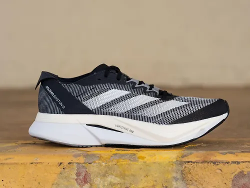 The Adidas Boston 12 sits on a wood table.