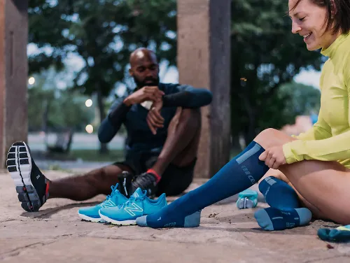 Two runners put on CEP socks before a run.