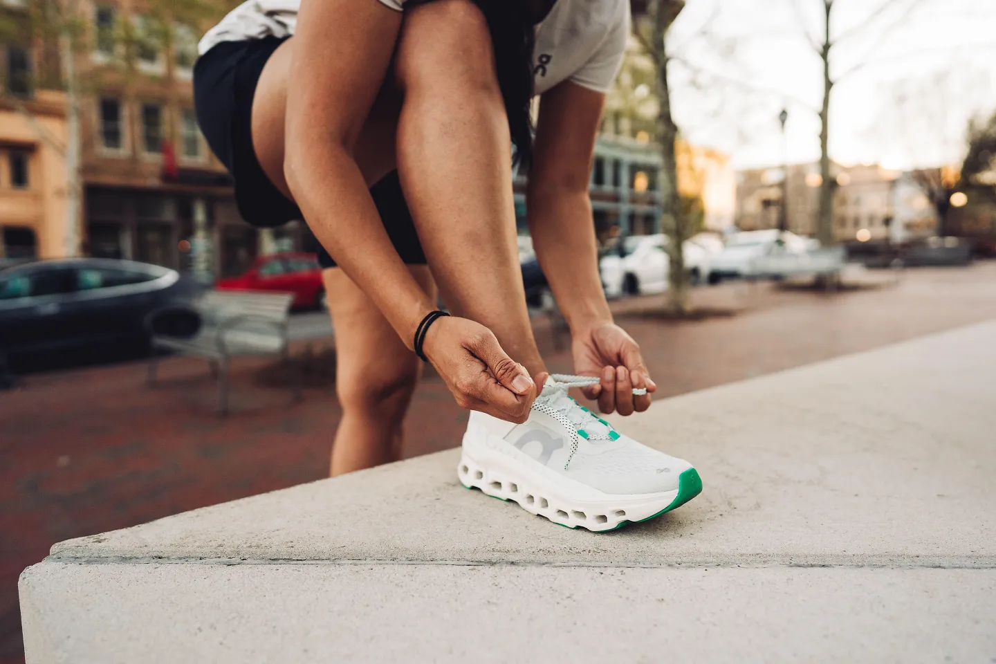 A runner props their foot up on a bench to lace up the On Cloudmonster.