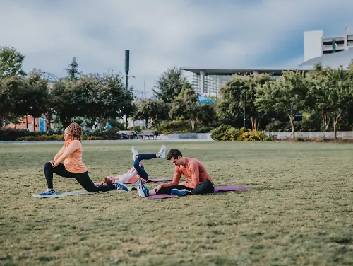 Runners stretch on a grassy lawn.