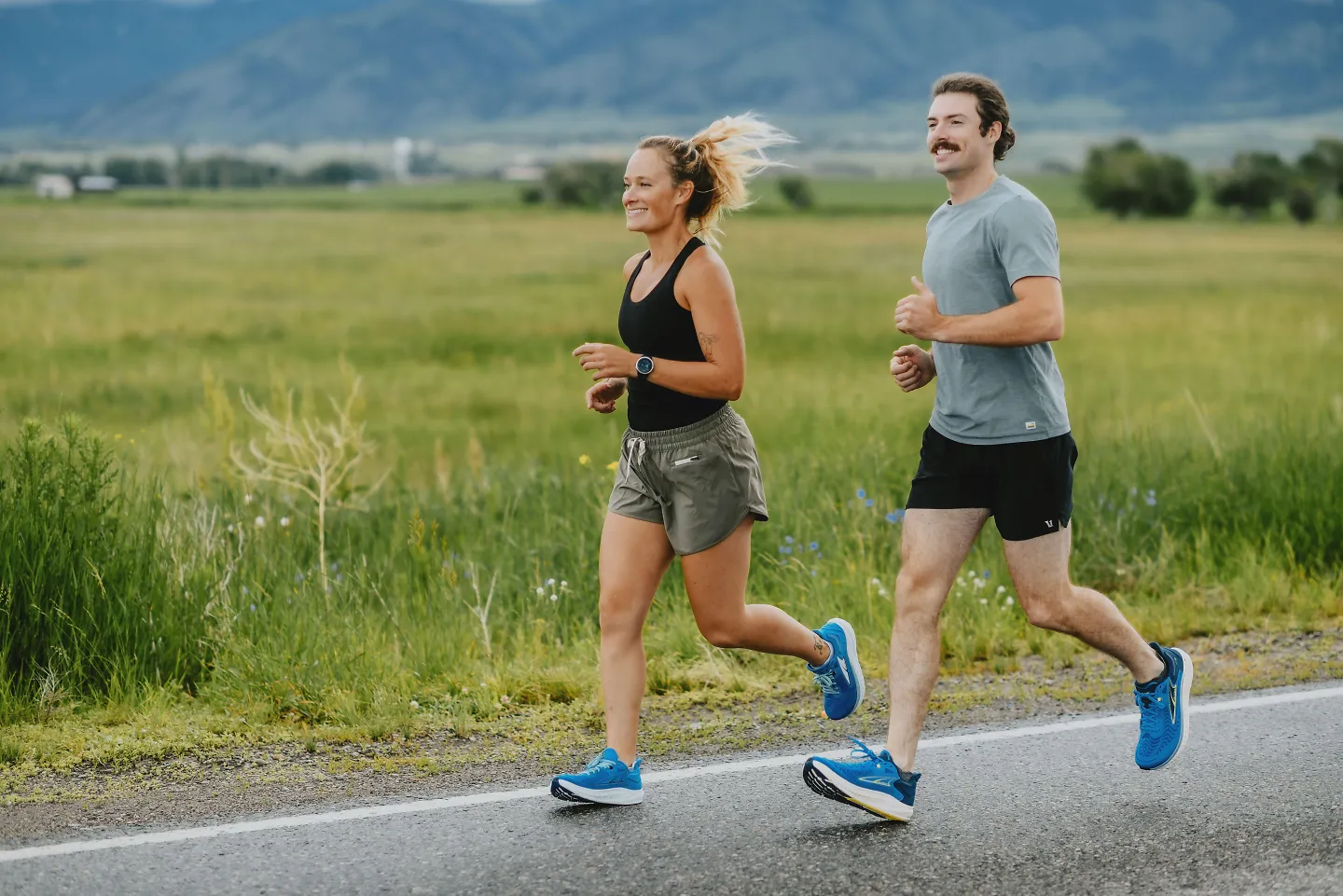 A man and woman run along a country road.