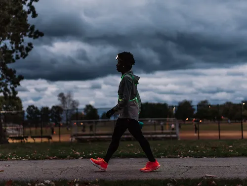 A woman walks on a pathway at dusk.