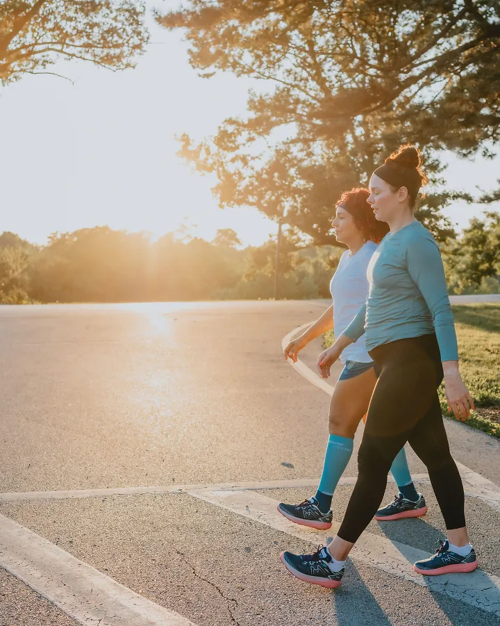 Two women walk together as the sun rises.