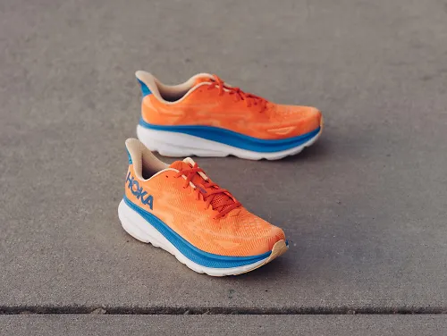 A pair of men's HOKA Clifton 9 sit on the concrete. 
