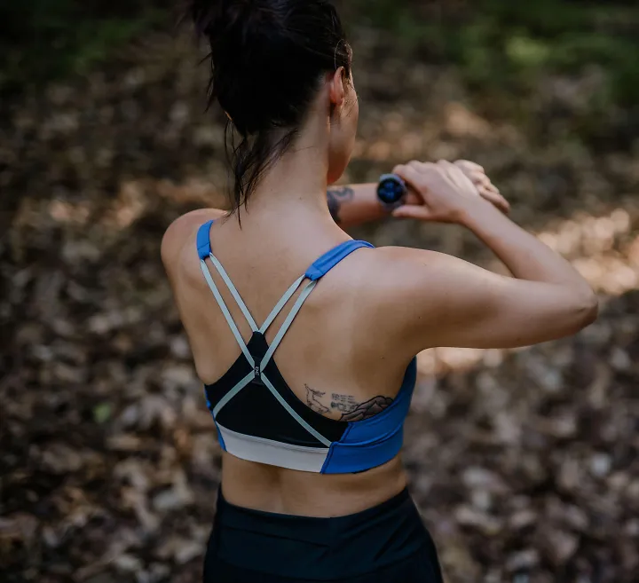 A runner wearing a sports bra starts her watch before a run.