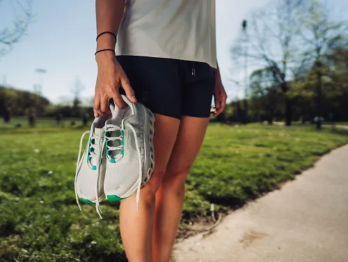 A runner holding a pair of the On Cloudmonster.