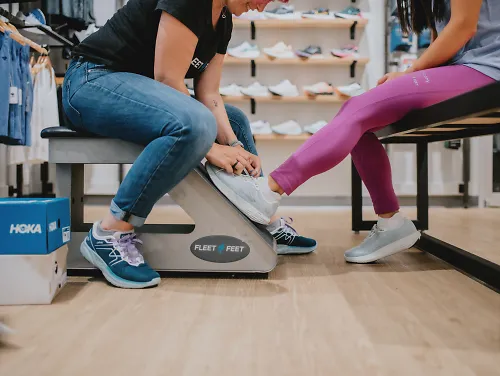 A Fleet Feet outfitter helps a customer try on shoes.