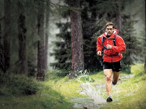 A man running on a trail through the woods
