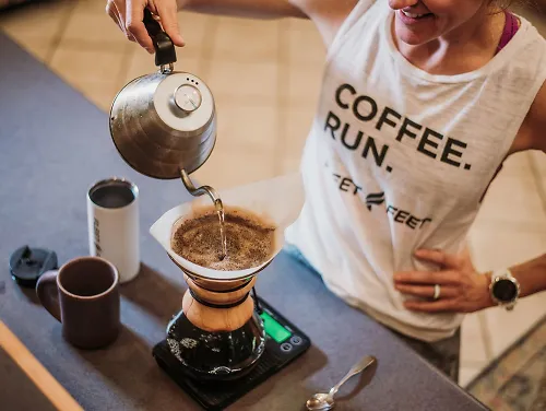 A woman pours coffee into a coffee machine. 