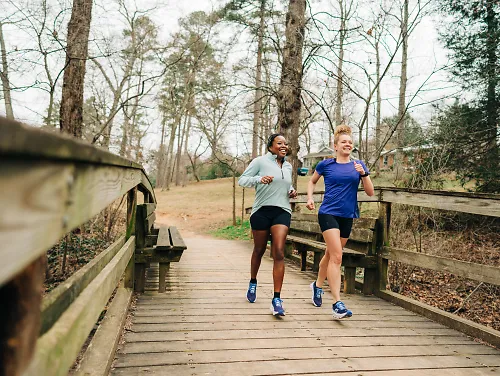 Two women run along a bridge.