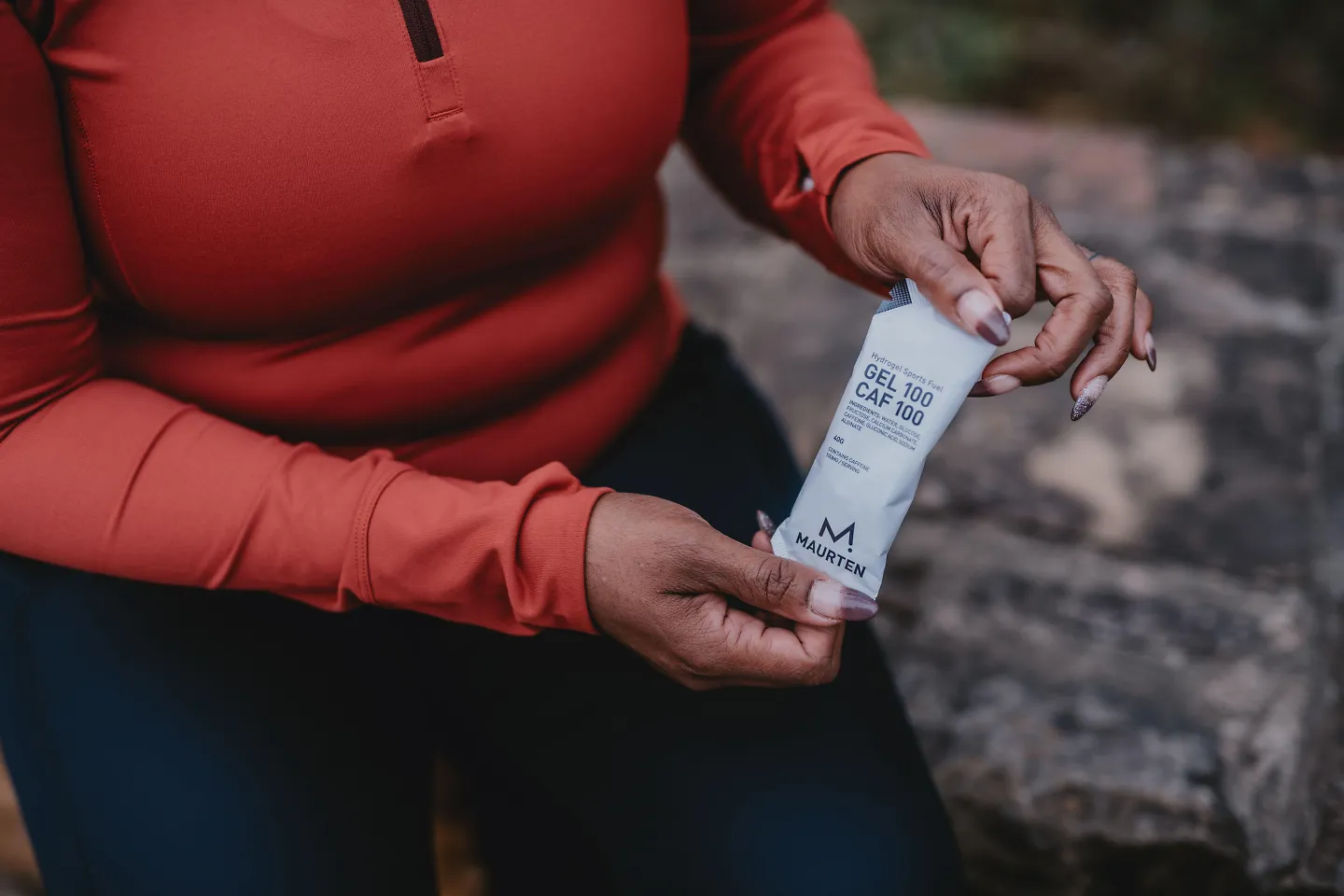 A woman holds up a Maurten Caf gel. 