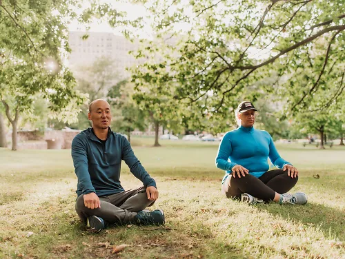 Two runners enjoy meditation in a park.