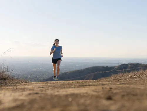 Nadia runs amongst a backdrop of sky and mountains.