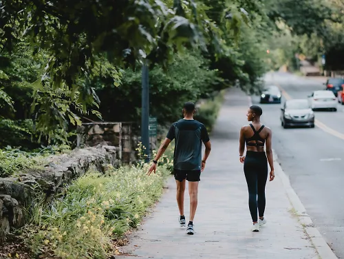 A man and woman walk down the street wearing On's latest Fall apparel.