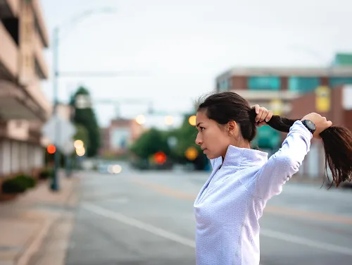 A runner tightens her ponytail before a run.