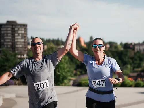 A man and woman hold hands during a race. 