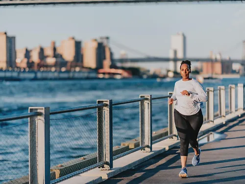 A woman runs along a waterfront pathway 