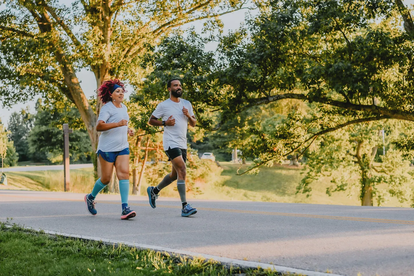 Two runners run down a street together.