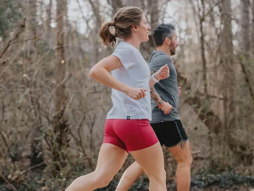 Two runners run on a pathway.