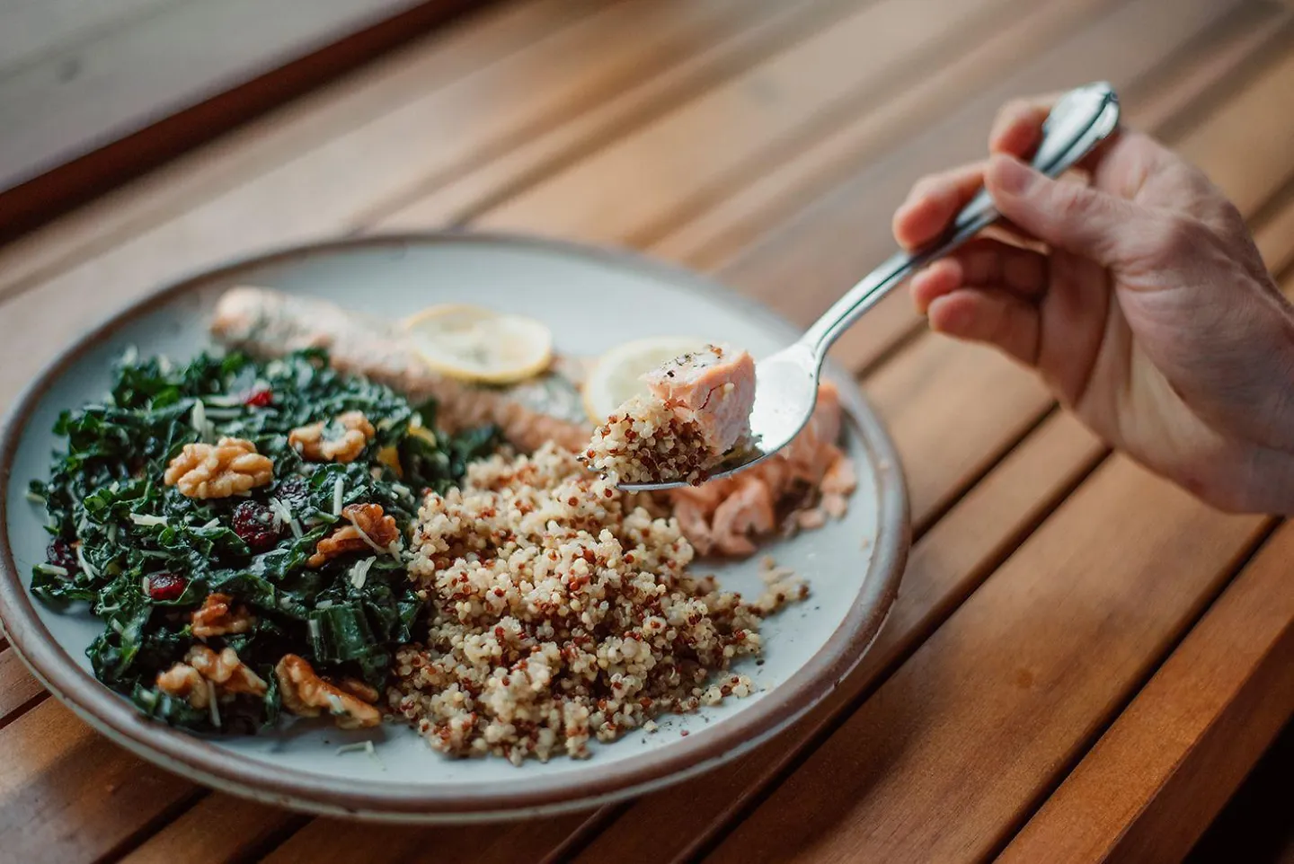 A plate of leafy greans, grains and salmon.