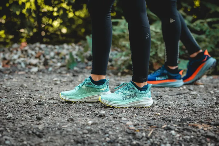 Two runners stand on a gravel trail.