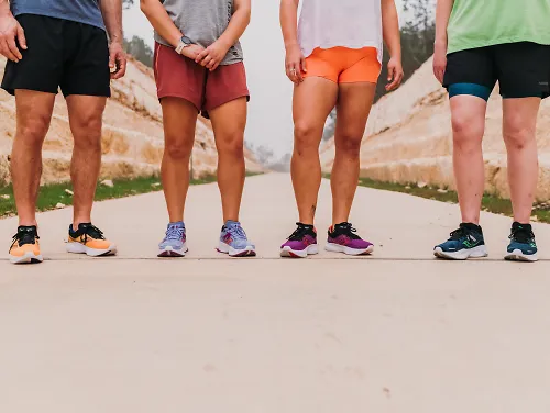 Four runners standing in saucony shoes on a sidewalk