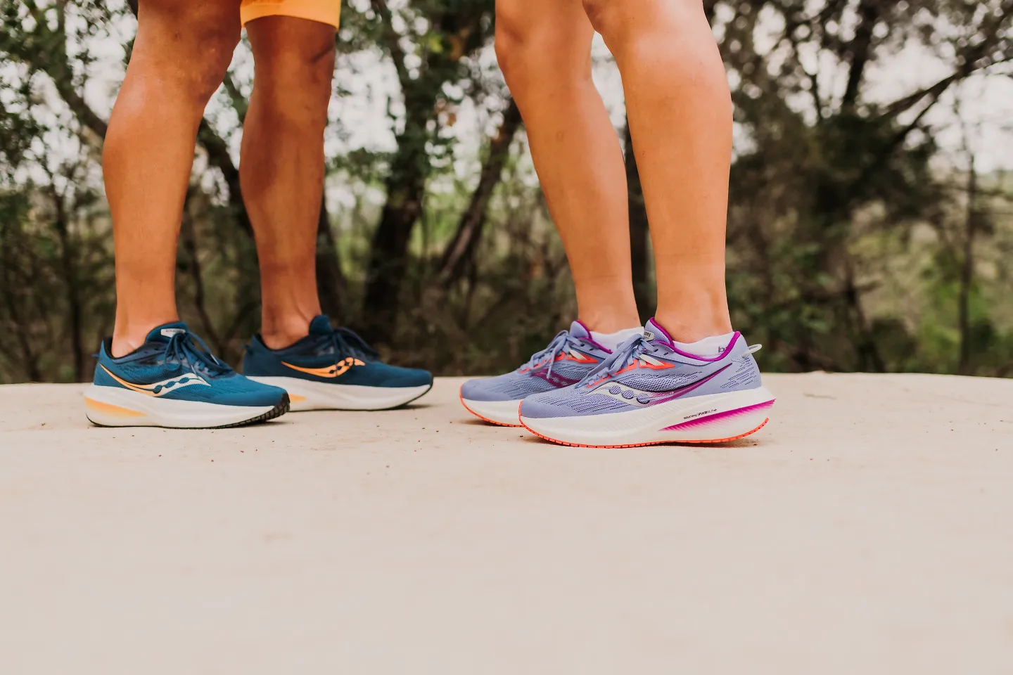 A man and woman standing in Saucony Triumphs (pictured from legs down)