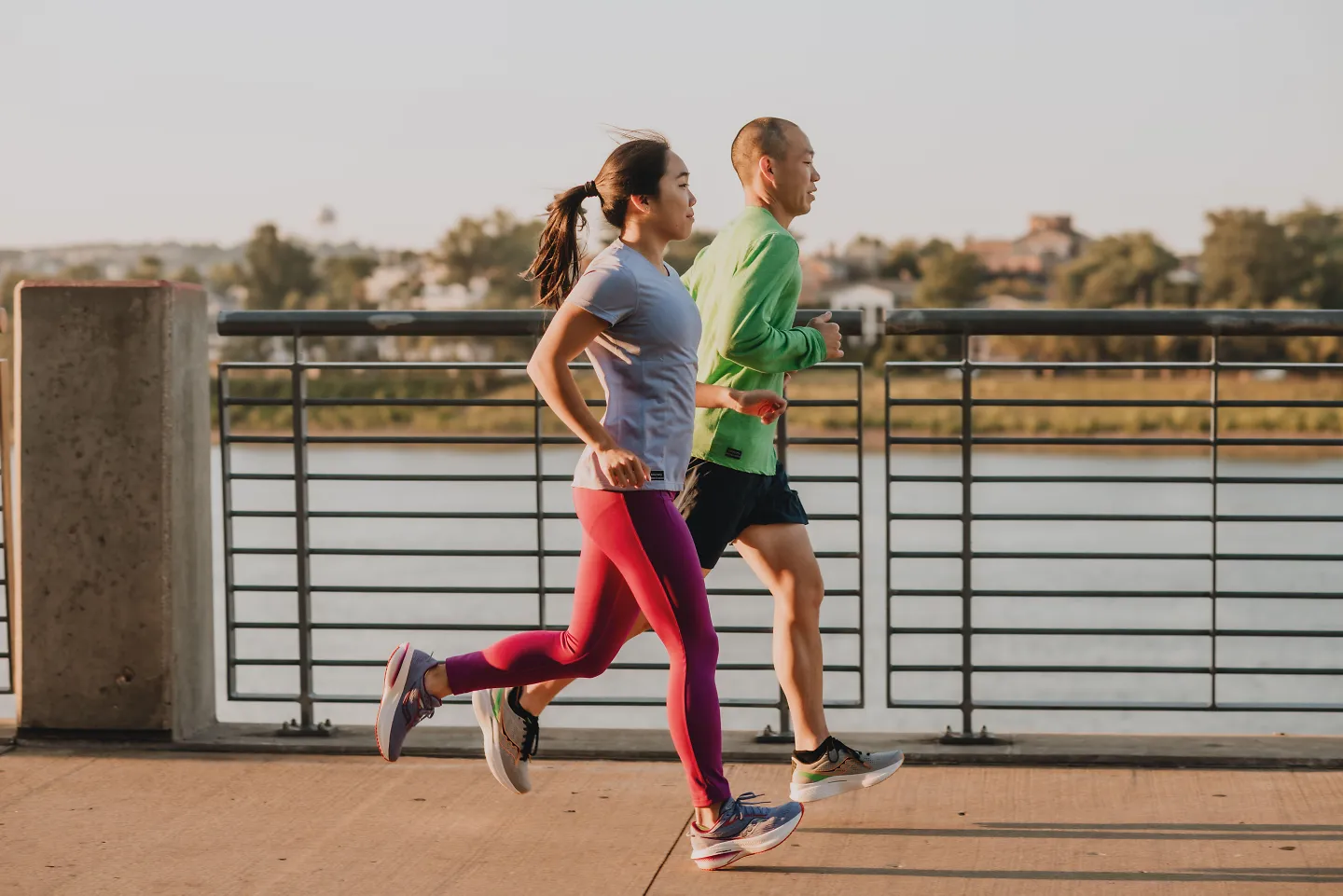 Two runners run side by side in the golden glow of a sunset.