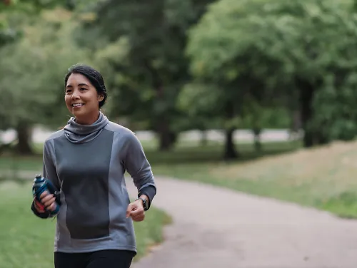A woman smiles as she runs down a path.