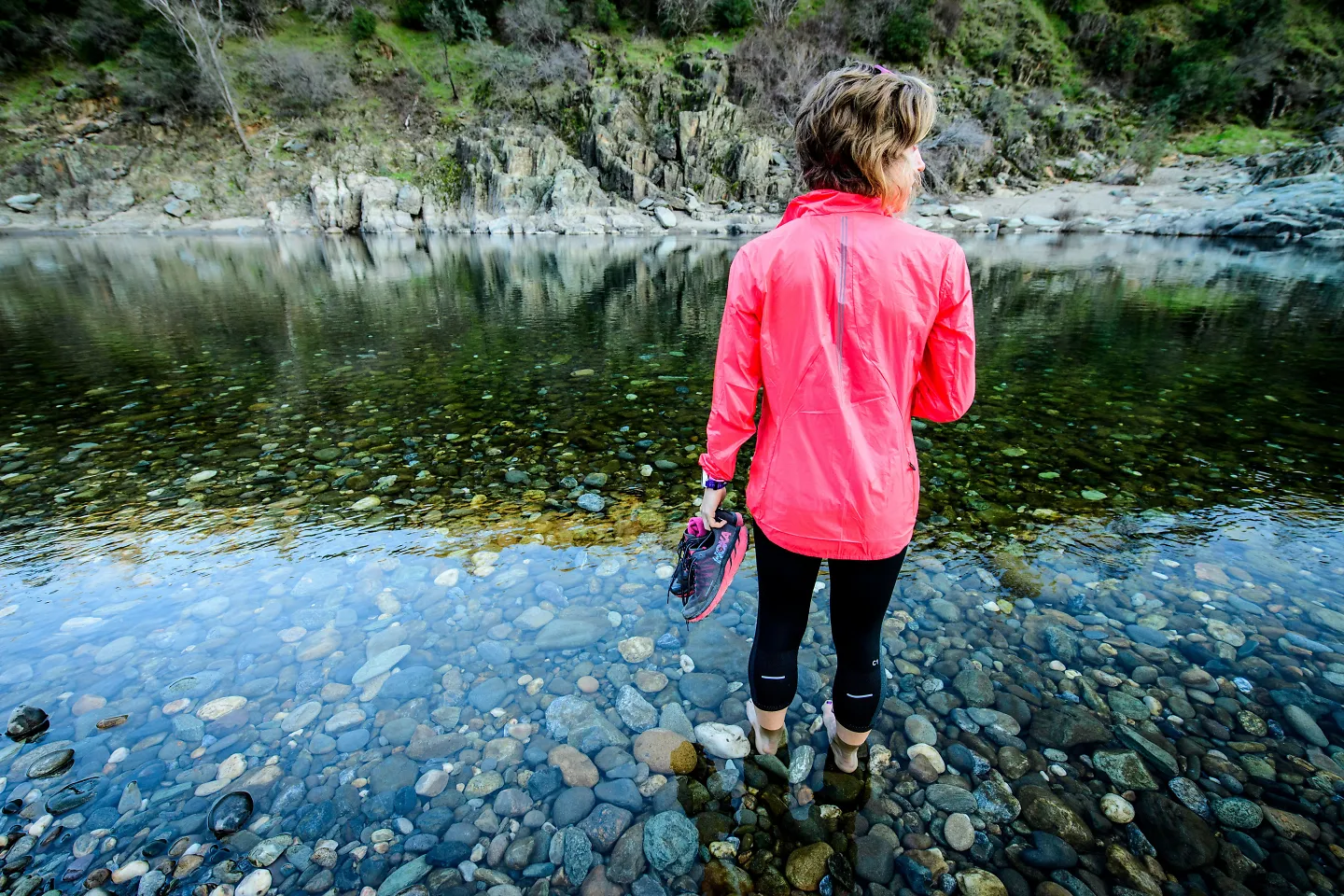 A woman soaks her feet in a stream. 