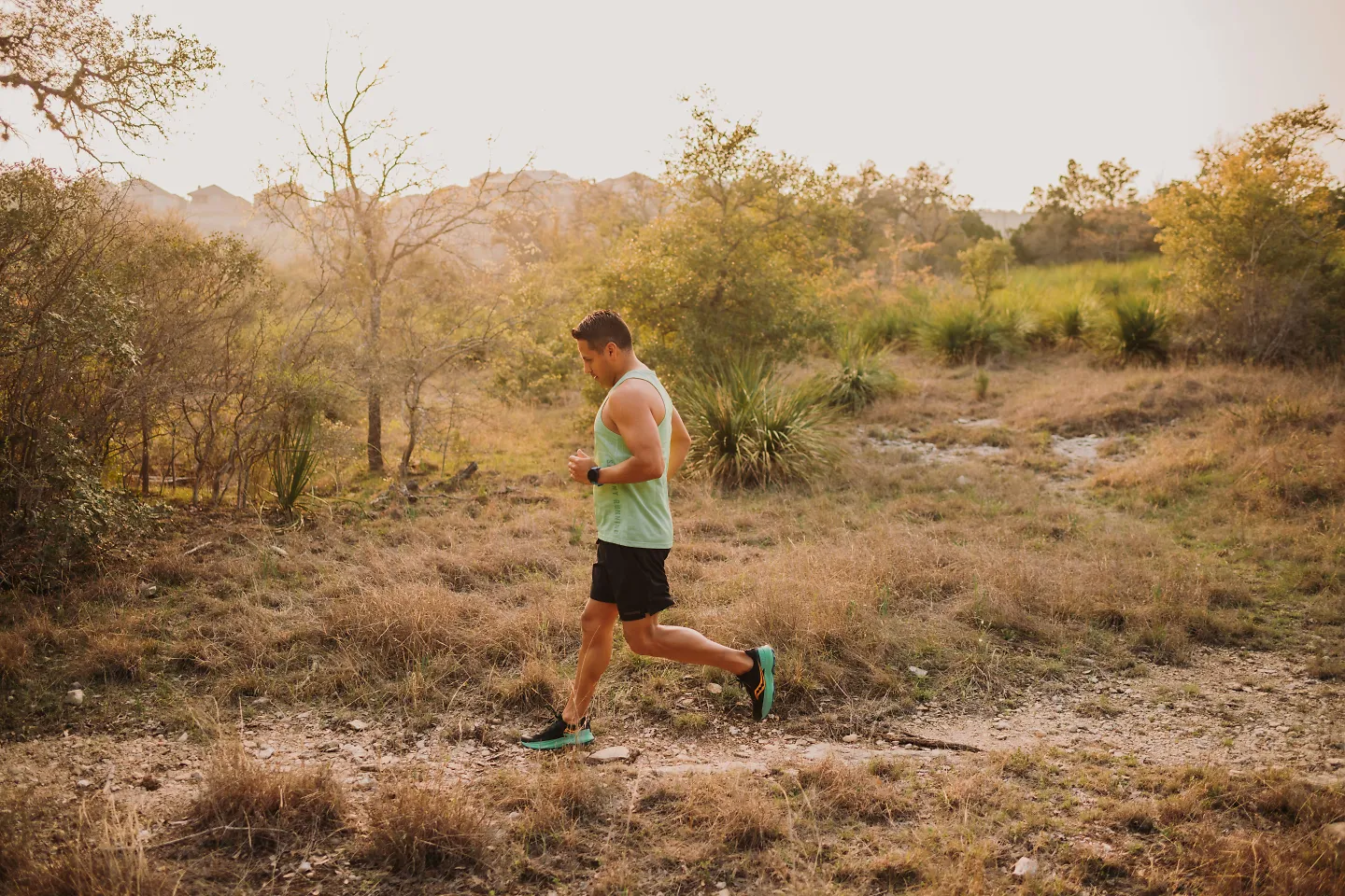 A man runs in the heat on a trail in an orange glow. 