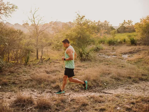 A man runs in the heat on a trail in an orange glow. 