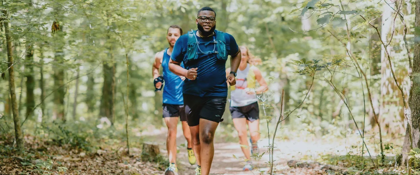 Runners run through the woods wearing trail running shoes.