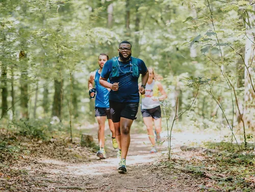 Runners run through the woods wearing trail running shoes.
