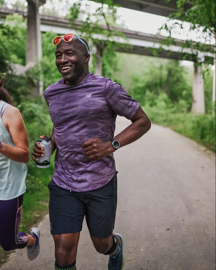 A man smiles as he runs along a path. 