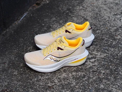 A pair of the yellow Saucony Triumph 21 sits on a grey road.