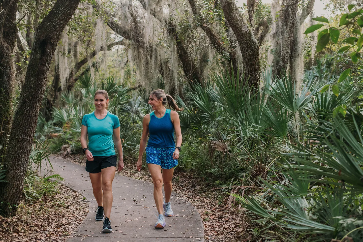 Two woman walk through a shaded path.