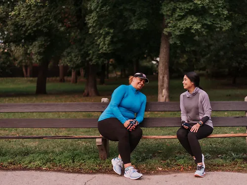 Two woman laugh on a park bench.