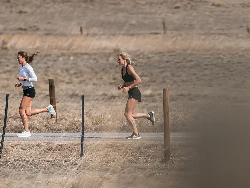 Cory McGee and Emma Coburn run on a dirt road