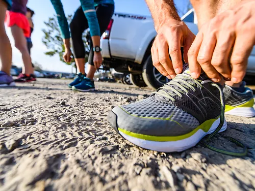 A runner tying a pair of Karhu running shoes