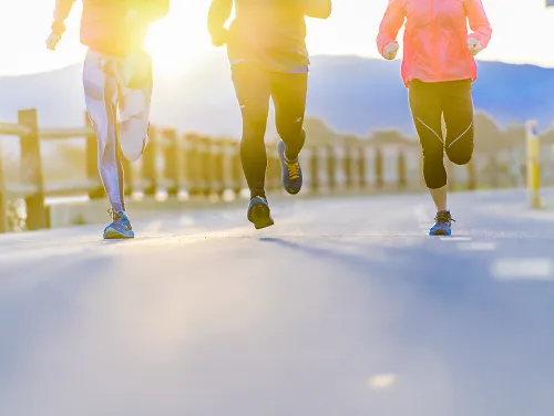 Three people run together on a paved path