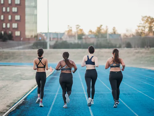 Four women running on a blue track