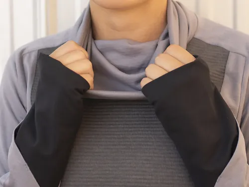 A woman tugs on the turtleneck of her On Weather Shirt