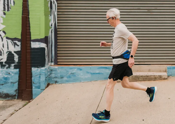 A man runs at an easy endurance pace in front of a mural