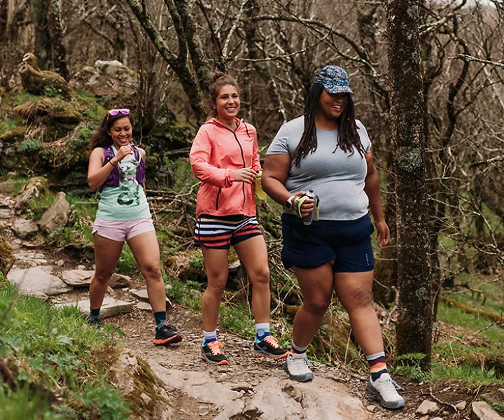 Three women smile as they run on a trail together