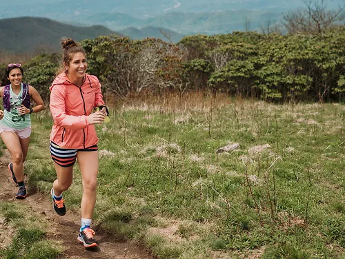 2 women smile as they summit a climb on a trail run 